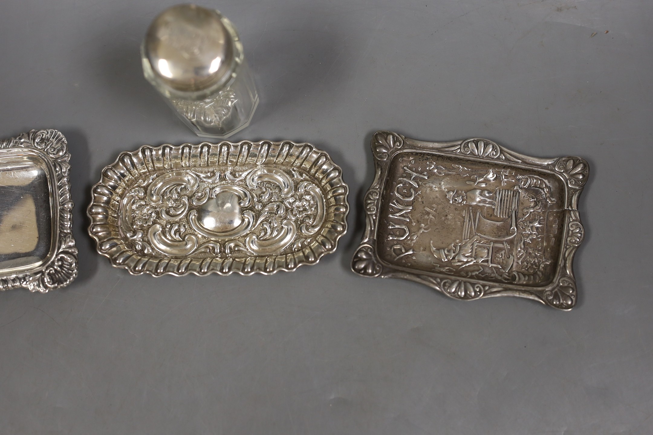 A late Victorian repousse silver 'Mr Punch' pin dish, Saunders & Shepherd, Birmingham, 1894, 10.7cm, one other silver dish, a silver mounted toilet jar and a plated small dish.